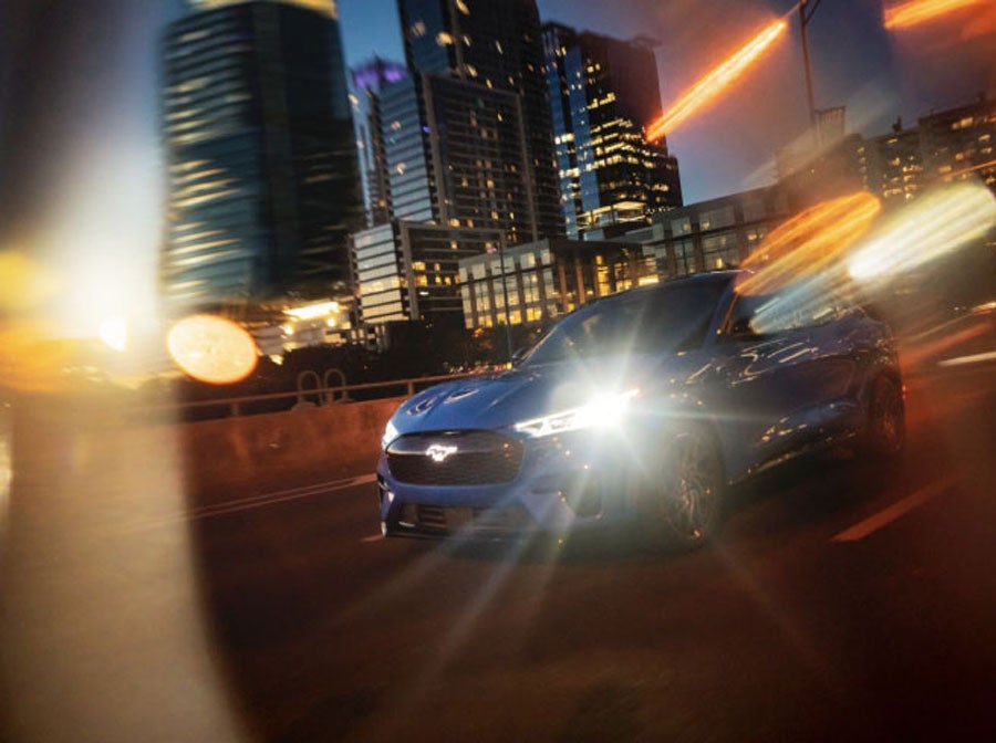 A Mustang Mach-E being driven in the city as the sun sets